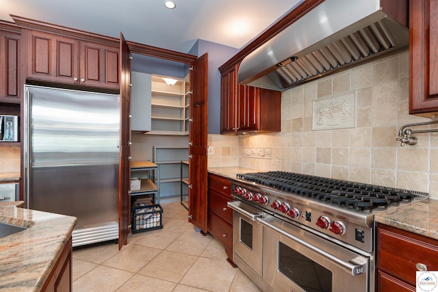 1114 W Broadway Blvd, Sedalia, MO 65301 - kitchen featuring high end appliances, wall chimney range hood, light tile patterned floors, backsplash, and light stone countertops