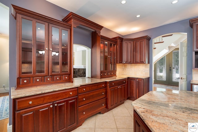 1114 W Broadway Blvd, Sedalia, MO 65301 - kitchen with arched walkways, backsplash, french doors, light stone countertops, and recessed lighting
