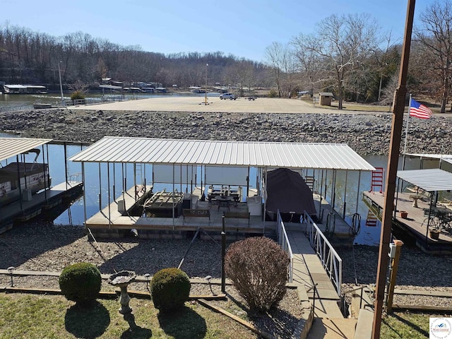 dock area featuring a wooded view, a water view, and boat lift