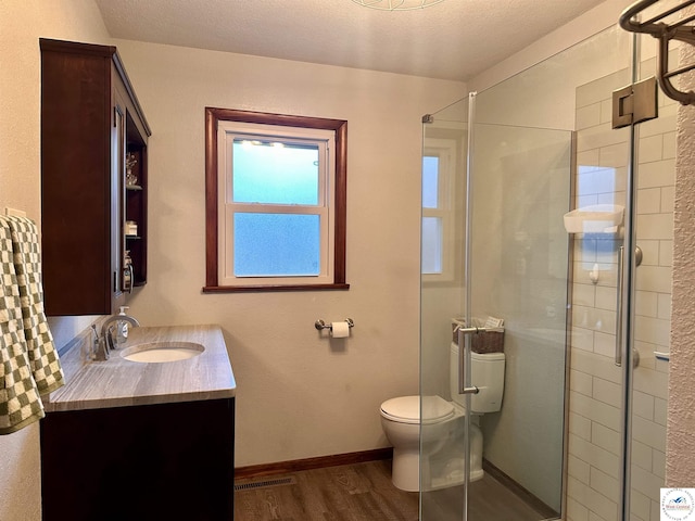 bathroom featuring visible vents, vanity, wood finished floors, toilet, and a stall shower