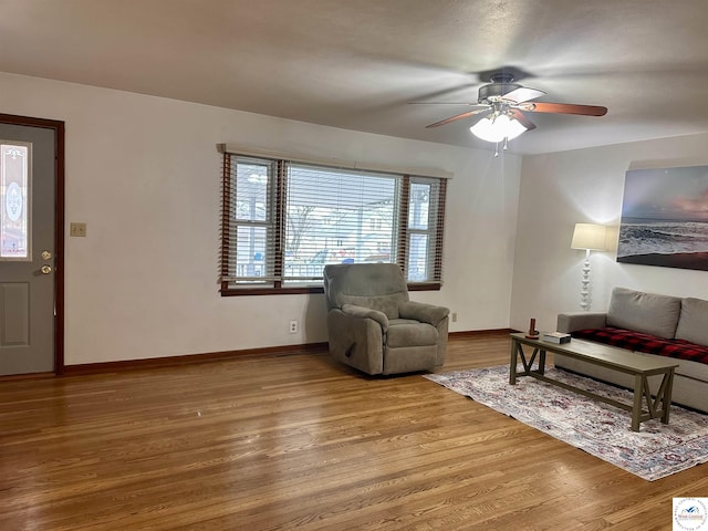 living room featuring baseboards, a ceiling fan, and wood finished floors