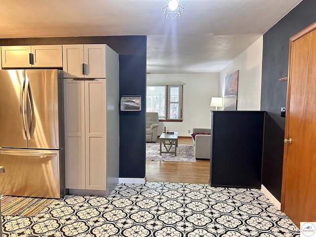 kitchen with freestanding refrigerator, white cabinetry, open floor plan, and baseboards
