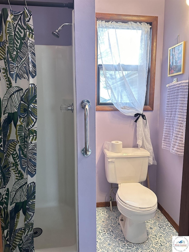 bathroom with baseboards, a stall shower, and toilet