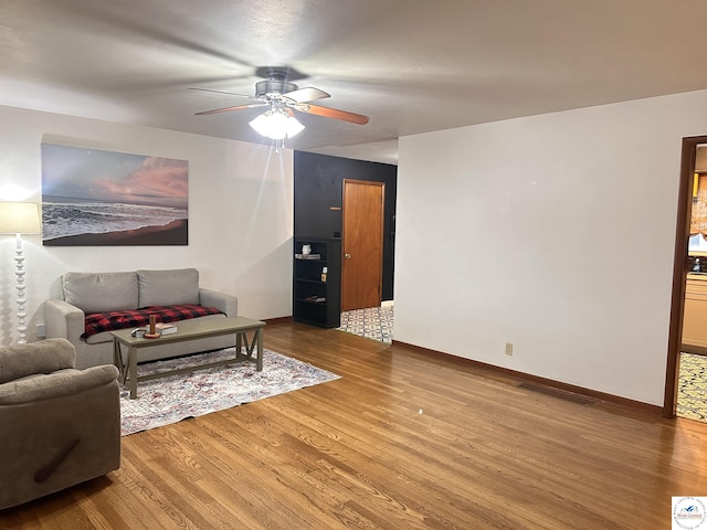 living room featuring baseboards, a ceiling fan, and wood finished floors