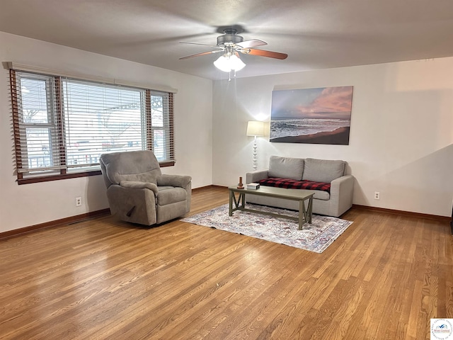 living room featuring light wood-type flooring, a ceiling fan, and baseboards