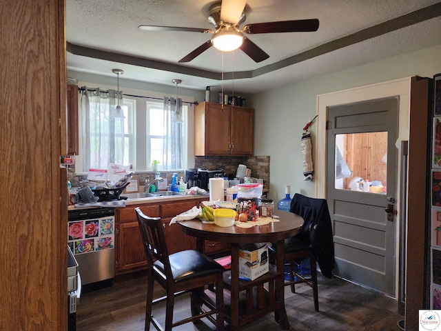 dining space with a tray ceiling, a ceiling fan, a textured ceiling, and dark wood-type flooring