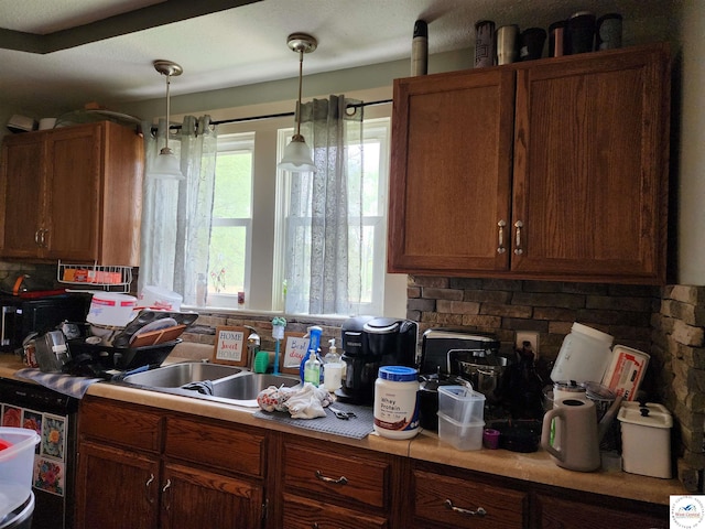 kitchen featuring decorative backsplash, hanging light fixtures, brown cabinets, light countertops, and a sink