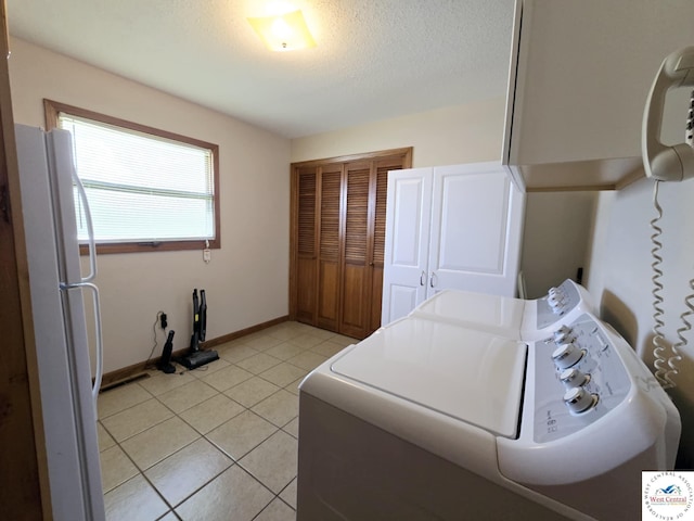 502 S Ferguson Ave, Tipton, MO 65081 - laundry area featuring cabinet space, a textured ceiling, baseboards, light tile patterned floors, and washer and clothes dryer