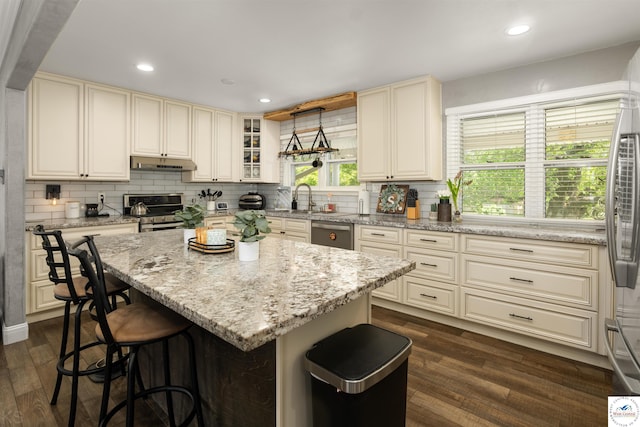 321 E 17th St, Sedalia, MO 65301 - kitchen with appliances with stainless steel finishes, under cabinet range hood, cream cabinets, tasteful backsplash, and recessed lighting
