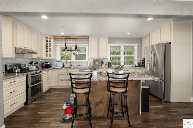 321 E 17th St, Sedalia, MO 65301 - kitchen featuring stainless steel appliances, cream cabinetry, healthy amount of natural light, and recessed lighting