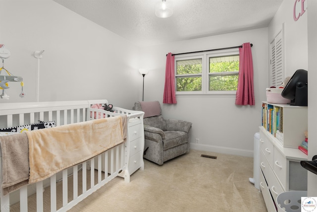321 E 17th St, Sedalia, MO 65301 - bedroom featuring a textured ceiling, light colored carpet, baseboards, and a crib