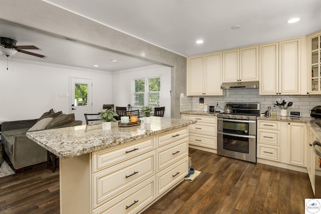 321 E 17th St, Sedalia, MO 65301 - kitchen with cream cabinetry, range with two ovens, under cabinet range hood, ornamental molding, and open floor plan