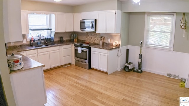 715 Hickory St, Warsaw, MO 65355 - kitchen featuring stainless steel appliances, a sink, light wood-style floors, and white cabinets
