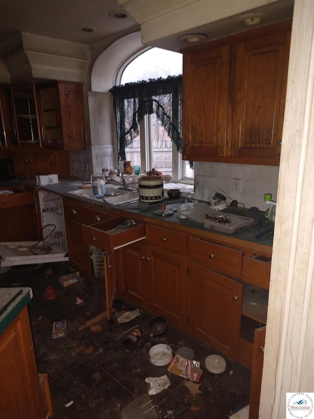kitchen with brown cabinetry, backsplash, and dark countertops