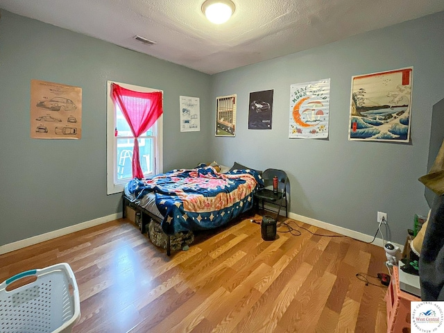 bedroom featuring wood finished floors, visible vents, and baseboards