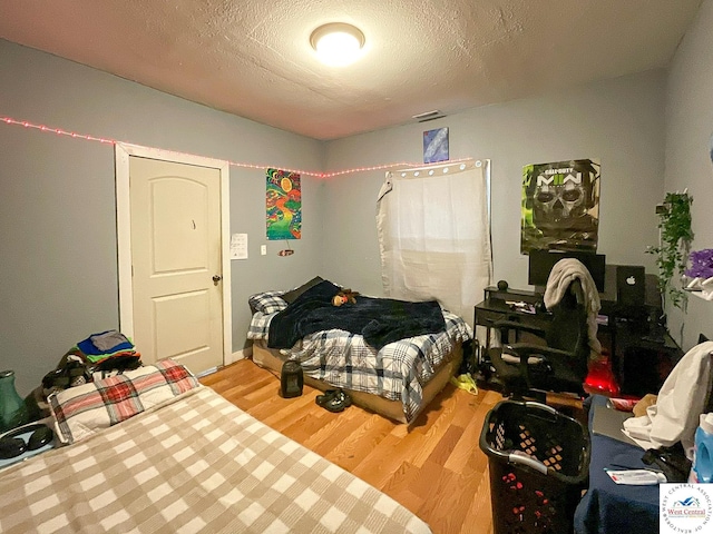 bedroom with a textured ceiling and light wood-style floors