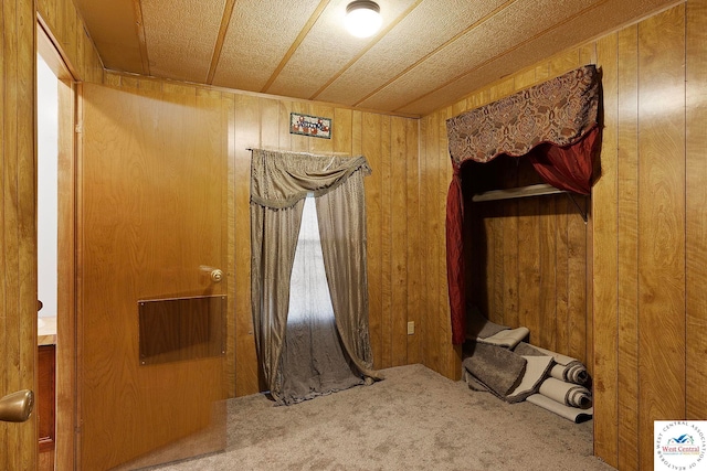 unfurnished bedroom featuring carpet flooring and wood walls