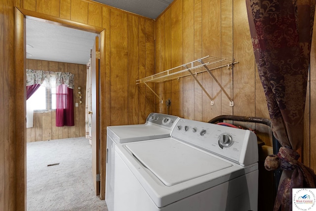washroom featuring carpet, wood walls, laundry area, and washer and clothes dryer