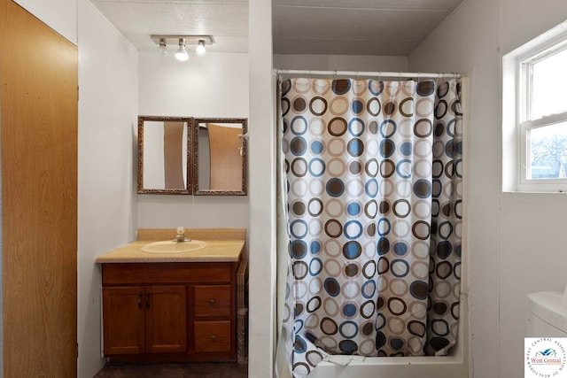 bathroom with track lighting, shower / bathtub combination with curtain, and vanity