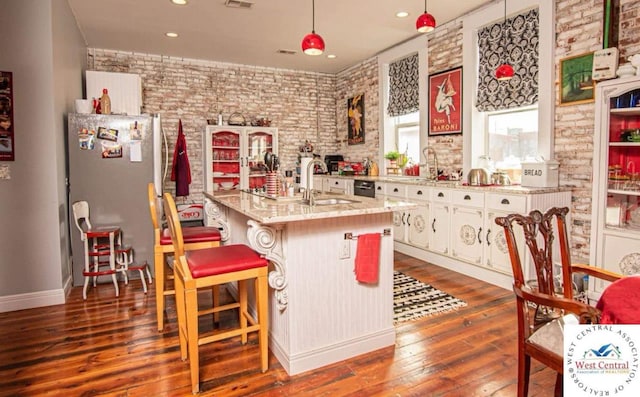304 W Main St, Sedalia, MO 65301 - kitchen with a sink, fridge, dark wood finished floors, white cabinetry, and brick wall