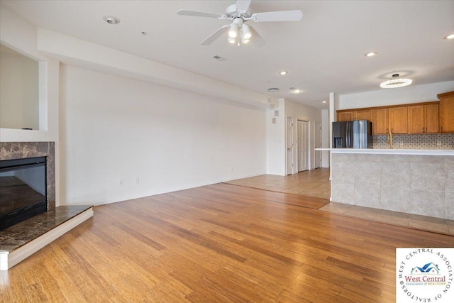 unfurnished living room with recessed lighting, light wood-style floors, a high end fireplace, visible vents, and a ceiling fan