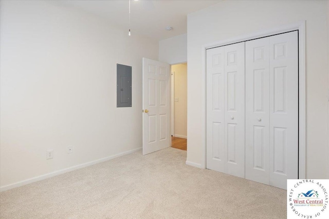 unfurnished bedroom featuring a closet, baseboards, electric panel, and carpet flooring