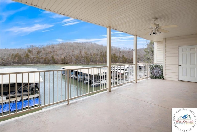 view of patio / terrace with ceiling fan, a forest view, and a water view