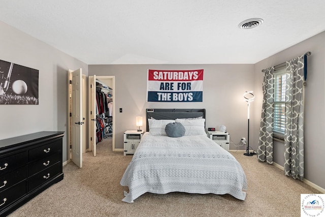 bedroom featuring visible vents, baseboards, carpet flooring, and a walk in closet
