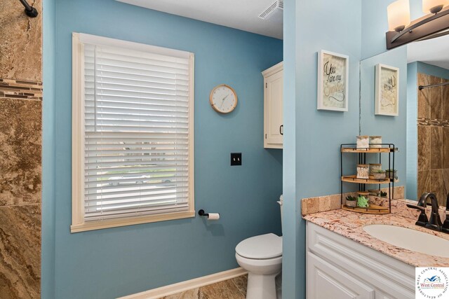 full bath with visible vents, baseboards, toilet, vanity, and tiled shower