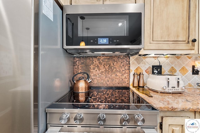 kitchen with light stone countertops, light brown cabinets, stainless steel appliances, and decorative backsplash