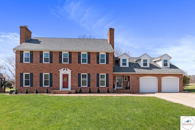 colonial inspired home featuring a chimney, a garage, a front lawn, and concrete driveway