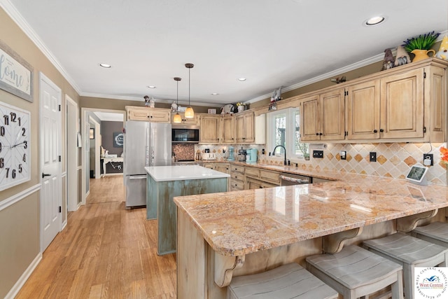 kitchen with a sink, a breakfast bar, light wood-style floors, stainless steel appliances, and a kitchen island