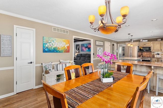 dining space with crown molding, visible vents, light wood-style floors, baseboards, and a notable chandelier