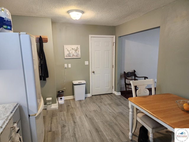 810 E Cedar St, Clinton, MO 64735 - dining area with light wood finished floors, a textured ceiling, and baseboards