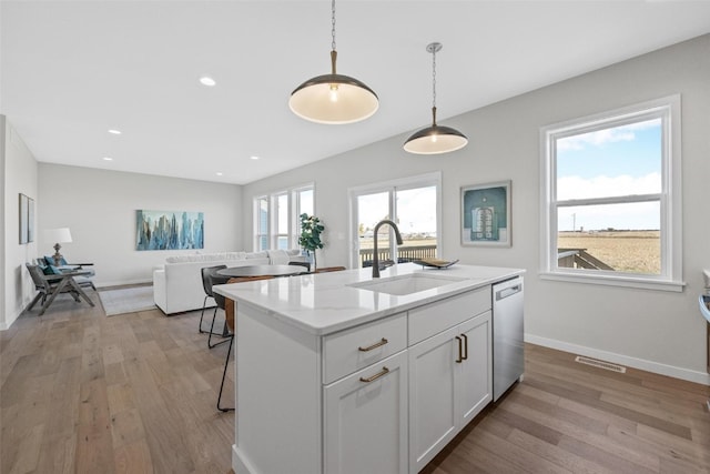 kitchen with white cabinets, sink, a wealth of natural light, and a kitchen island with sink