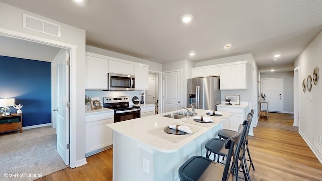 kitchen featuring white cabinets, appliances with stainless steel finishes, a kitchen island with sink, and sink