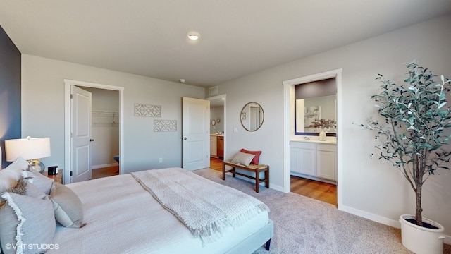 bedroom with a closet, a spacious closet, light colored carpet, and connected bathroom