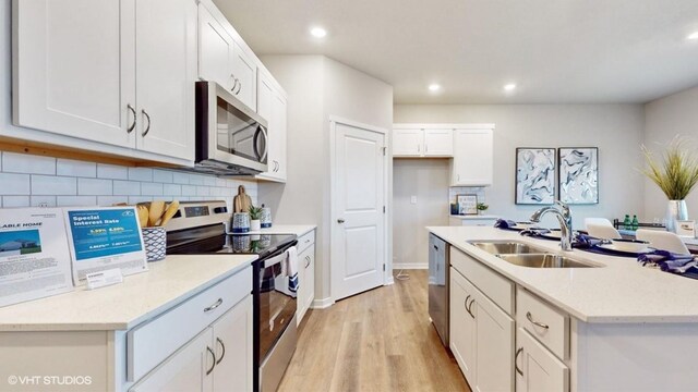 608 Maddie Ln, Tiffin, IA 52340 - kitchen with white cabinetry, a sink, an island with sink, light wood finished floors, and appliances with stainless steel finishes