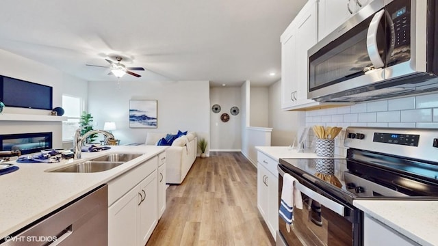 608 Maddie Ln, Tiffin, IA 52340 - kitchen with open floor plan, white cabinetry, backsplash, a sink, and appliances with stainless steel finishes
