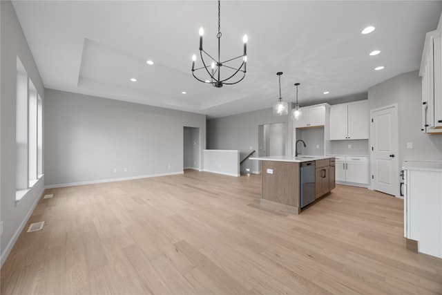 kitchen featuring dishwasher, light wood-type flooring, an island with sink, hanging light fixtures, and white cabinets