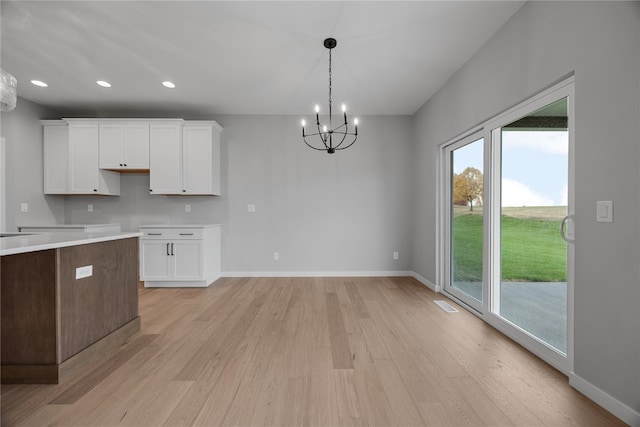 kitchen featuring a chandelier, white cabinets, decorative light fixtures, and light wood-type flooring