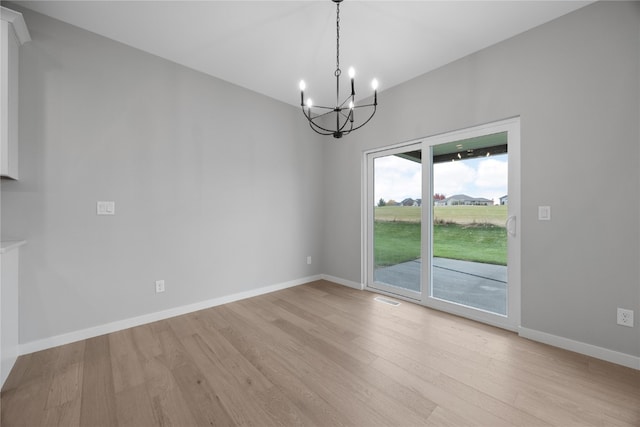 unfurnished room with light hardwood / wood-style flooring and a chandelier