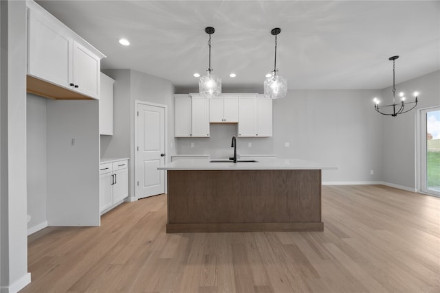 kitchen featuring white cabinetry, light hardwood / wood-style floors, sink, and decorative light fixtures