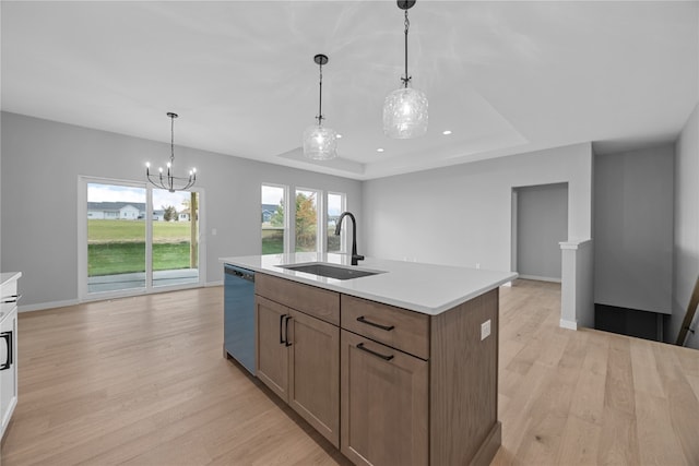 kitchen featuring light hardwood / wood-style floors, dishwasher, decorative light fixtures, and an island with sink