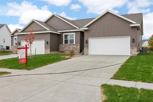 view of front of property with a front yard, a garage, and central air condition unit