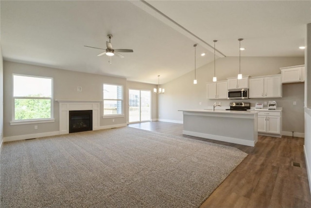 unfurnished living room with ceiling fan with notable chandelier, dark hardwood / wood-style floors, lofted ceiling, and sink