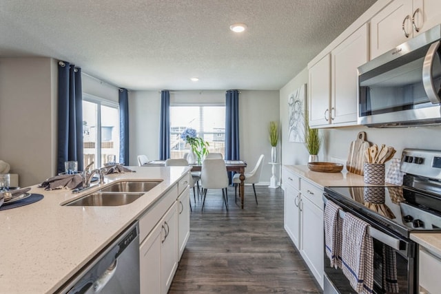 kitchen with a textured ceiling, stainless steel appliances, sink, dark wood-type flooring, and white cabinets