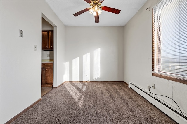 empty room with plenty of natural light, carpet flooring, ceiling fan, and a baseboard heating unit