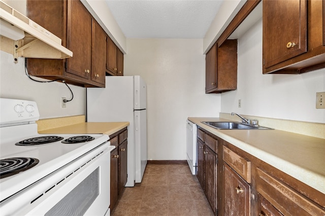 kitchen featuring white appliances, a textured ceiling, sink, dark brown cabinets, and dark tile floors