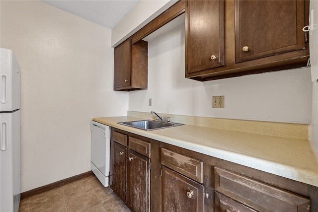 kitchen with white appliances, light tile flooring, sink, and dark brown cabinetry